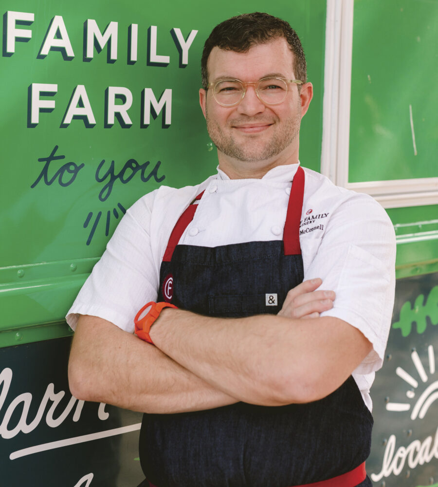 Portrait of a male chef with arms crossed in front of green food truck