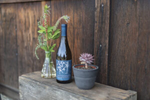 bottle of Matthiasson wine on table with plants and wood backdrop