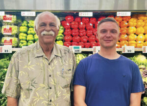 Proprietor of Sunshine Foods, Jay Smith with grandson, Jeffery standing in front of fresh fruits and vegetables