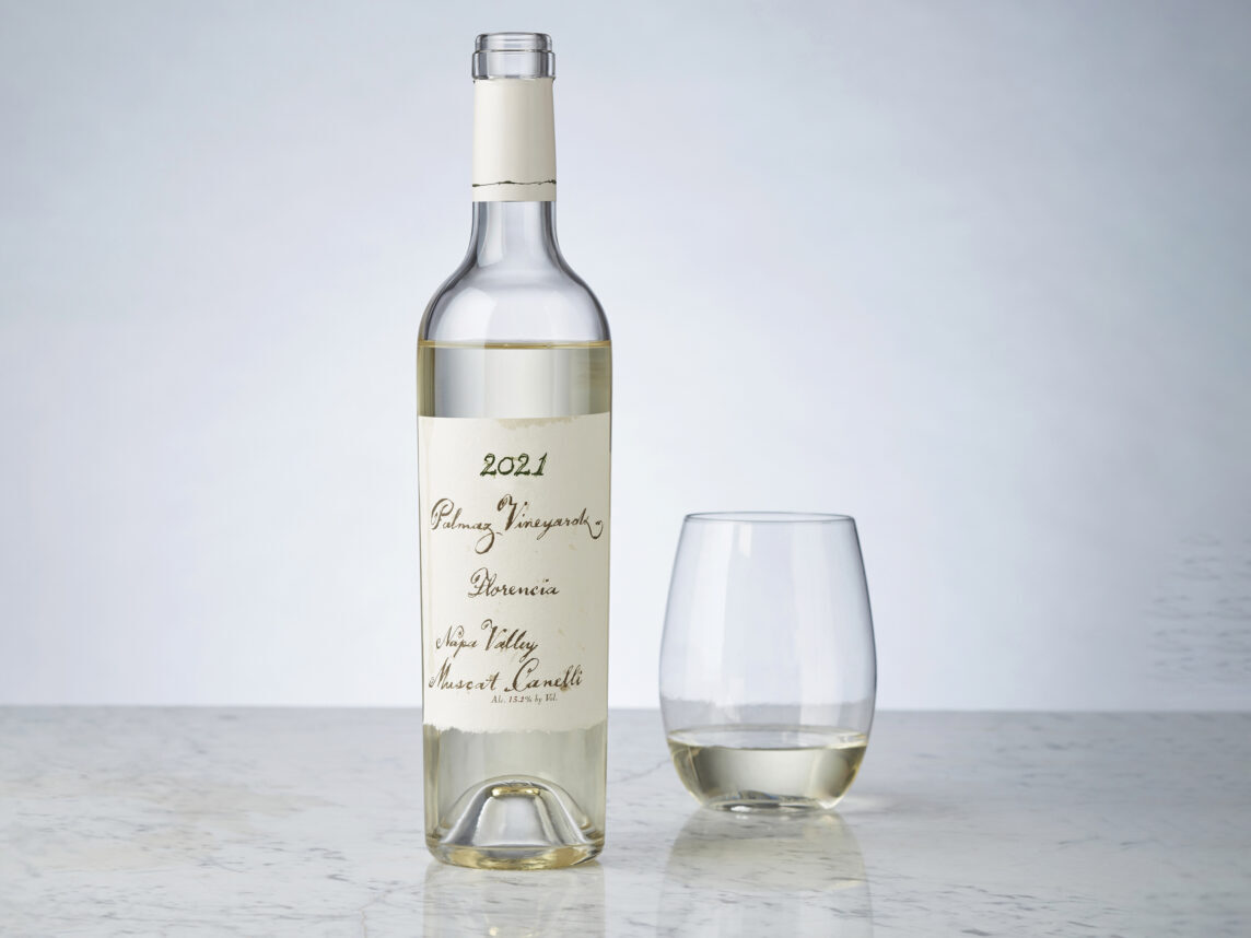 Bottle of white wine with wine glass on counter with gray background