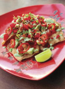 red plate with poke nachos with wedge of lime