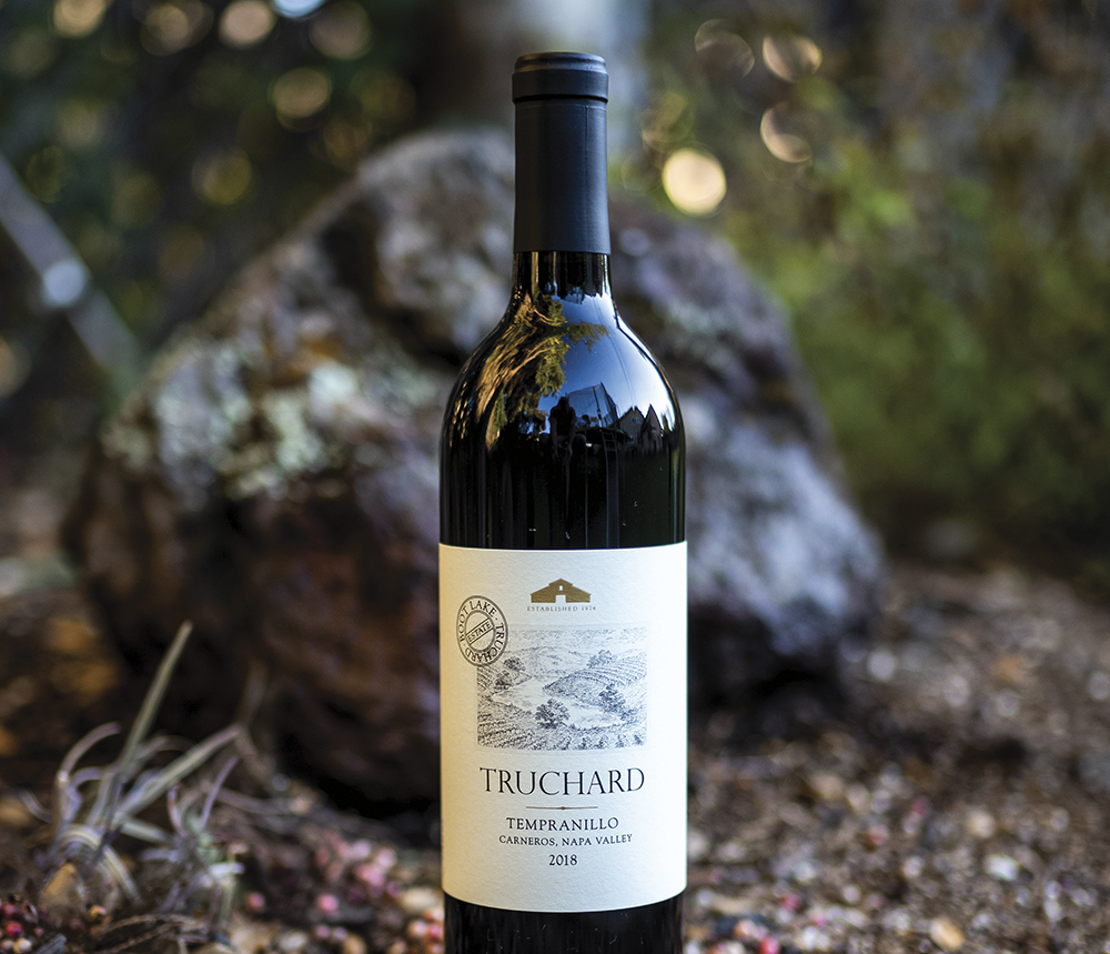 bottle of truchard wine on ground with rocks and greenery behind it