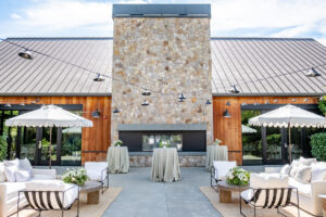 Exterior courtyard of The Estate Yountville with couches, tables, umbrellas and stone fireplace