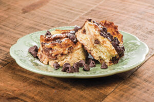 slice of chocolate chip bread pudding on blue plate on wood table
