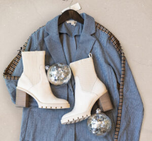 blue jacket with white boots and holiday ornaments laying on top