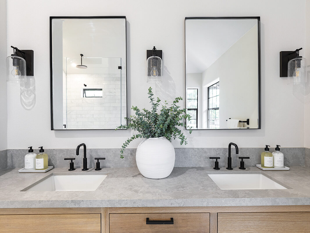 Interior of modern bathroom with neutral tones, 2 sinks , 2 mirrors and a potted plant