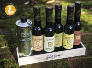 Salute Sante grapeseed oil collection on wooden tray in outdoor setting