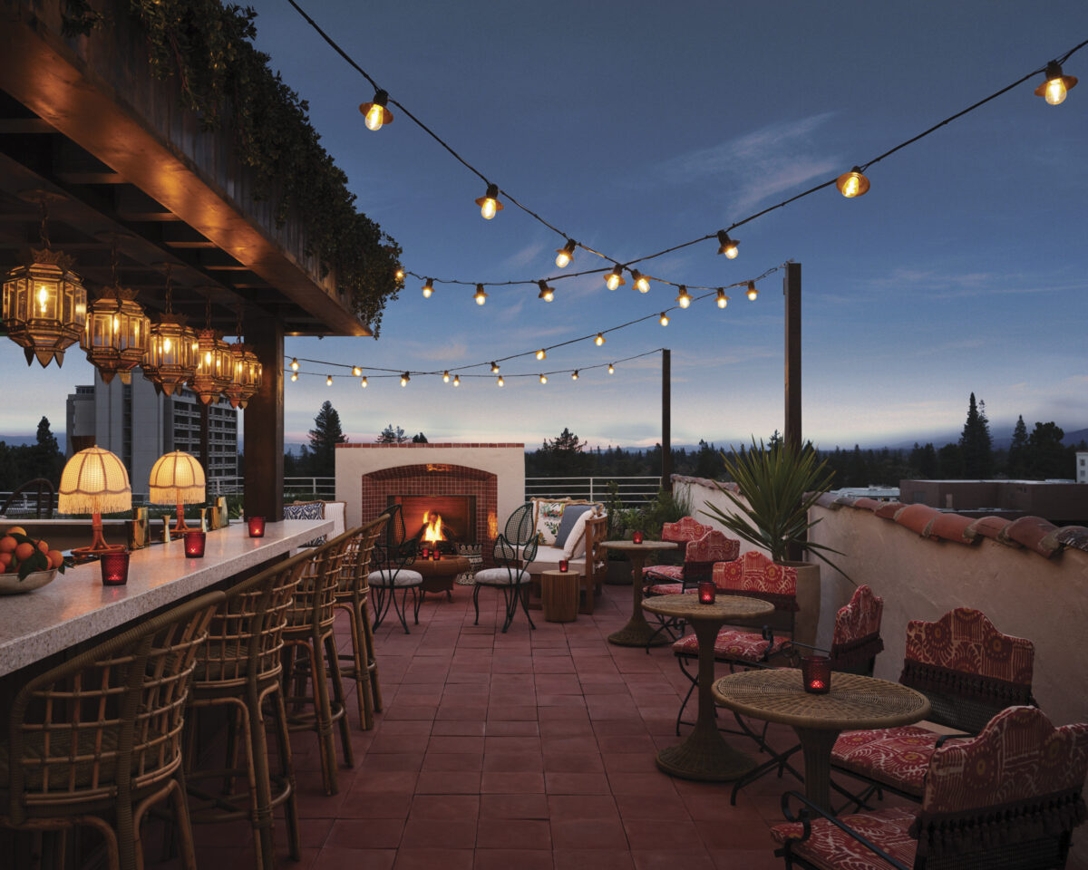 Graduate Palo Alto Presidents’ Terrace Rooftop Bar with outdoor seating, fireplace, bar and string lights in the evening