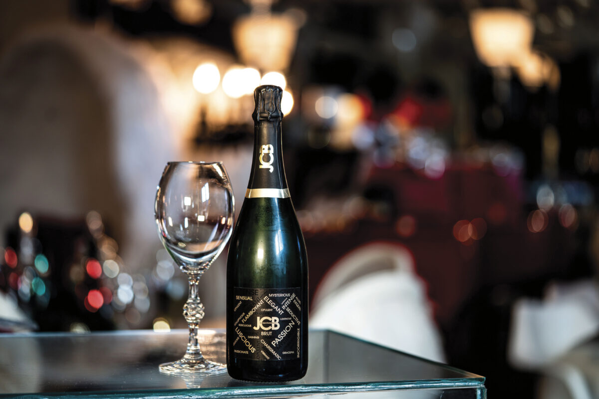 Bottle of JCB collection sparkling wine with glass on table