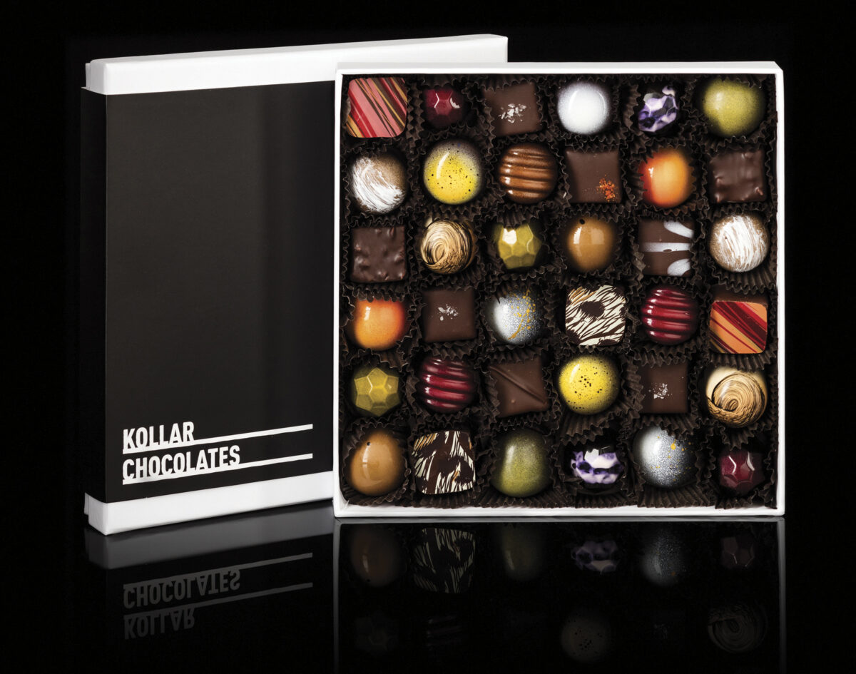 open box of colorful Kollar Chocolate pieces with black background