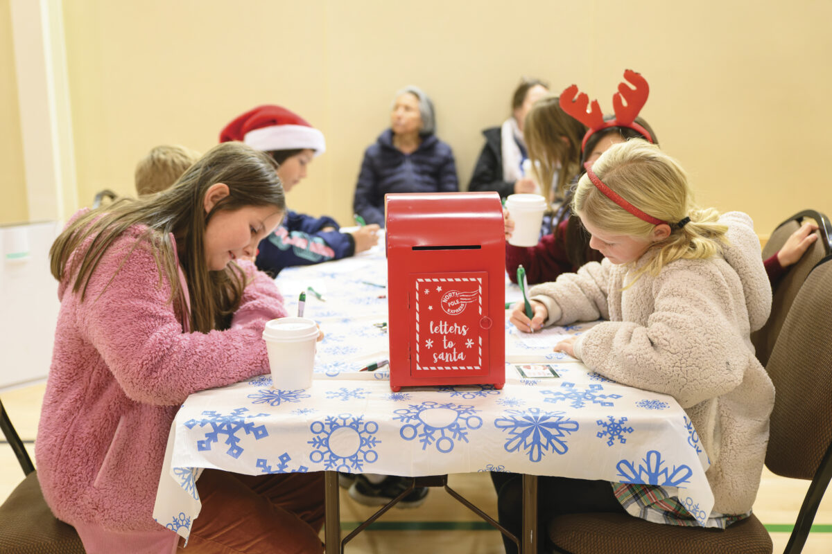 children sitting at table writing letters with red mailbox labeled "Letters to Santa" on the table