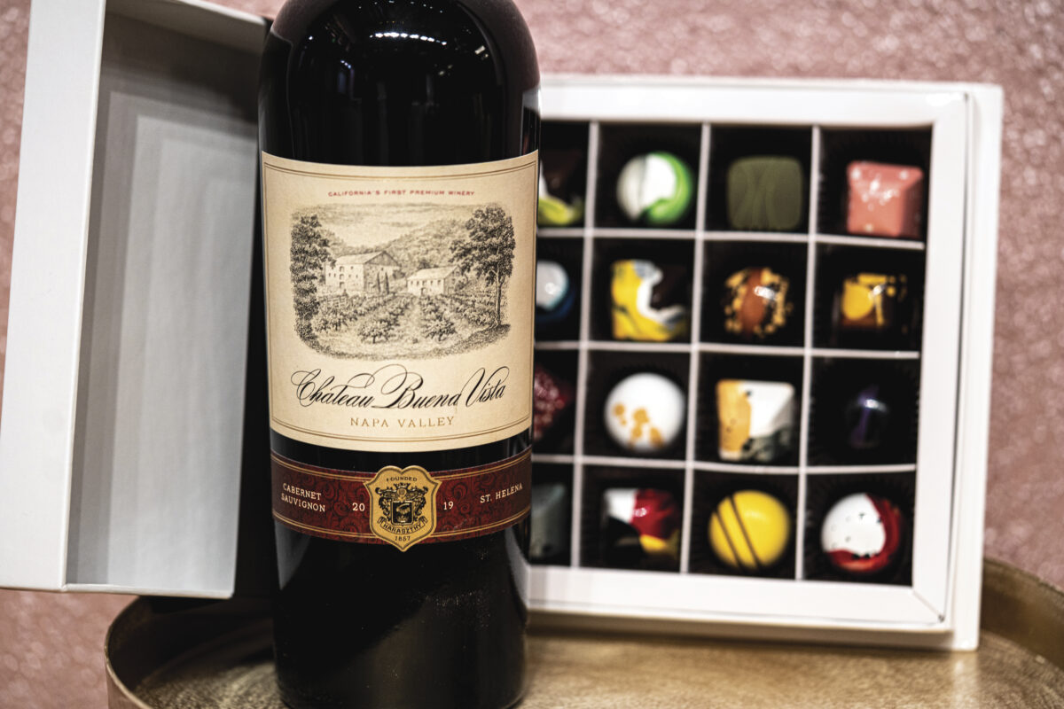 Bottle of Chateau Buena Vista in front of an open box of Earth & Sky chocolates in white box