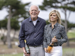 Rich and Leslie Frank standing outside, each holding a bottle of Frank Family Vineyards wine