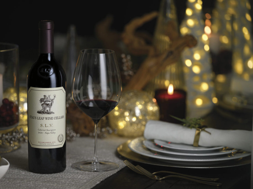Bottle of Stag's Leap Wine Cellars wine on a tabletop set for holiday with twinkle lights and red lit candle