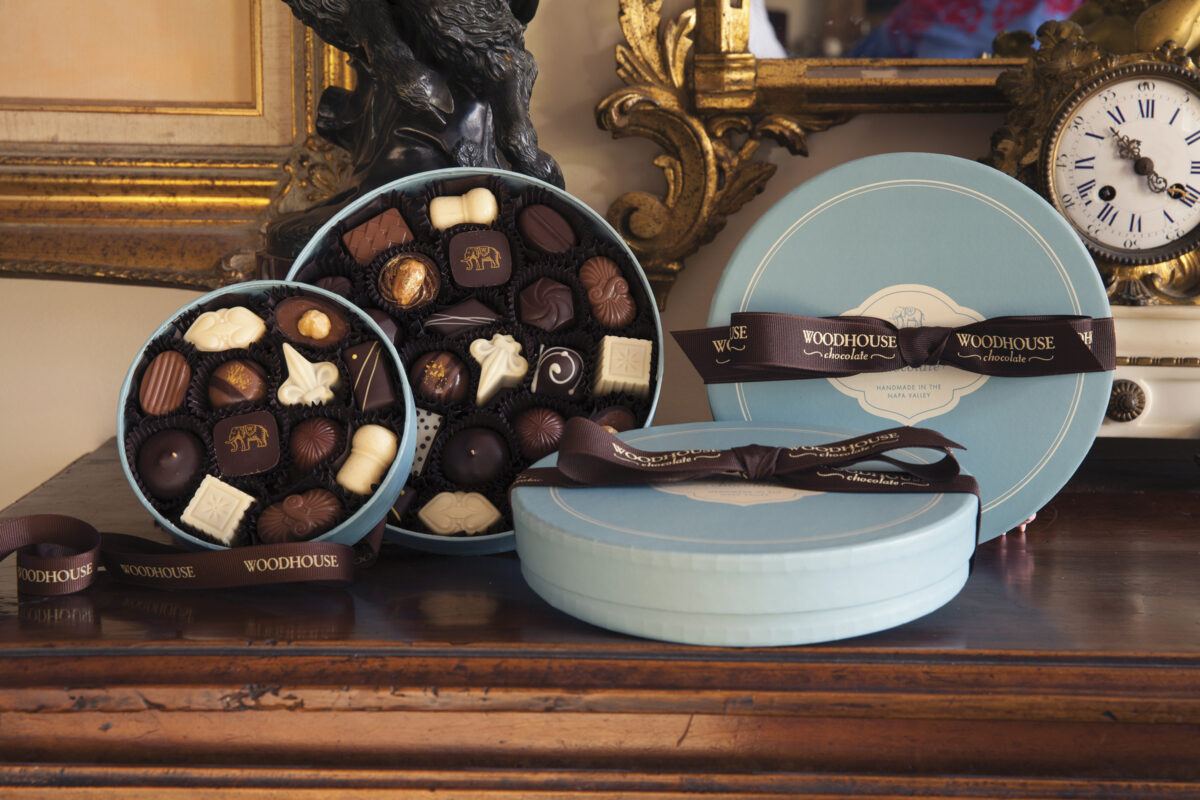 round boxes of chocolates in blue box with brown ribbon and 2 open boxes in various sizes