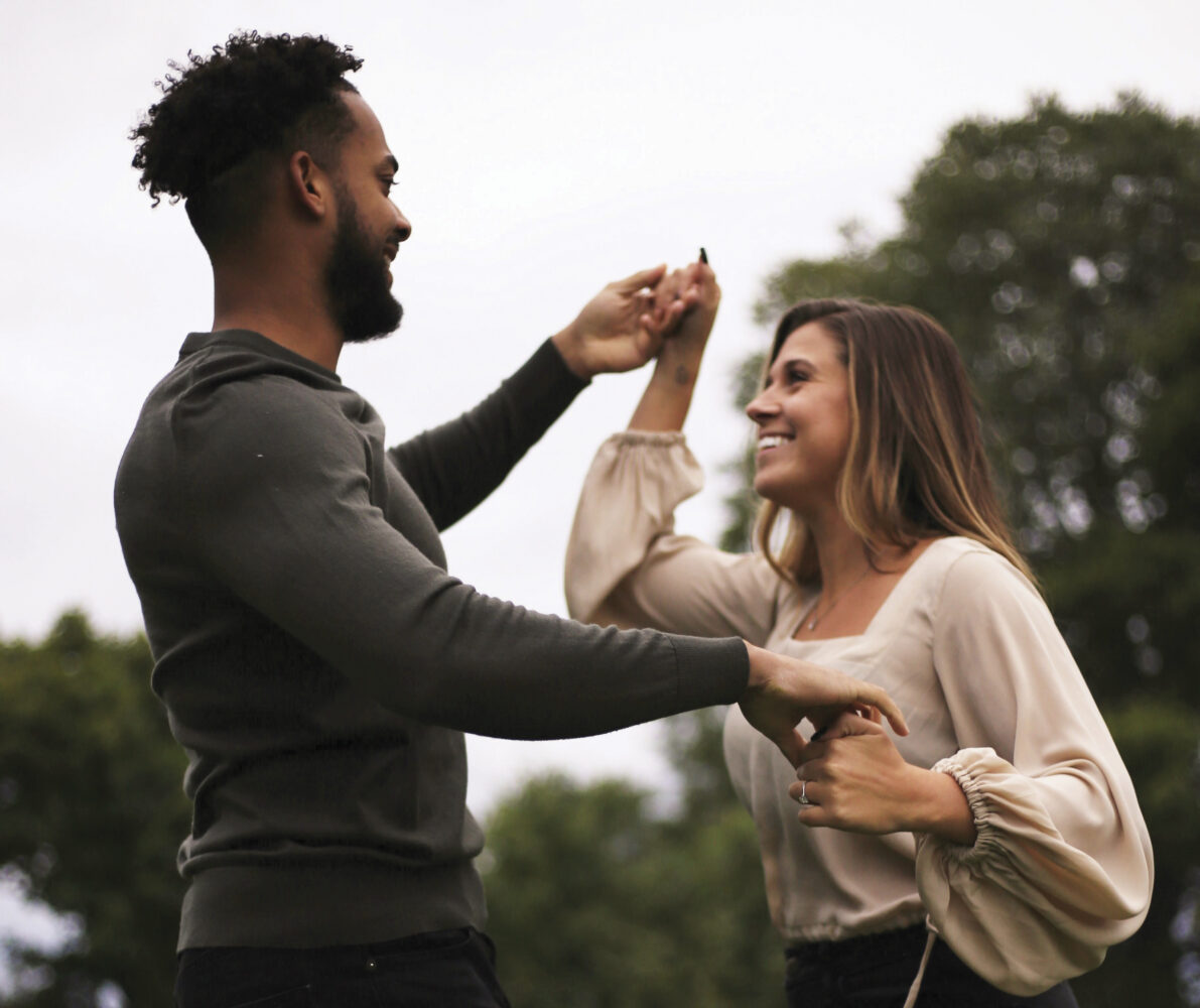 Man and woman dancing outside and smiling