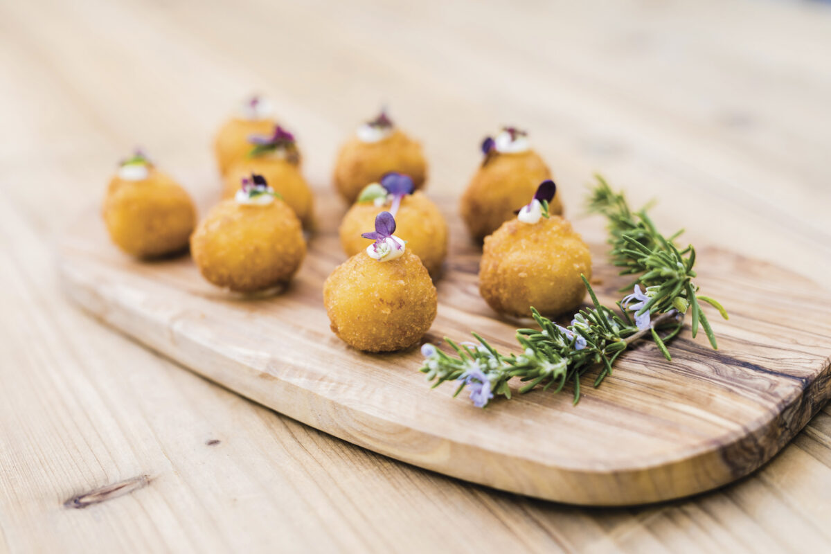 Arancini appetizer placed on wooden board on wood table