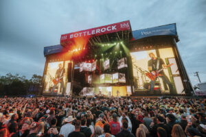 BottleRock stage with screens and banners displaying towards a crowd of festival goers with blue sky in the evening