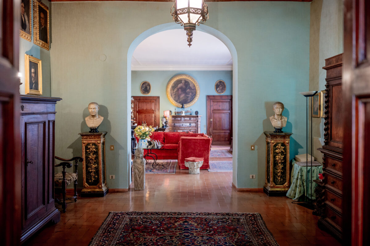 Palazzo Jacobini Foyer - showing antiques, marble busts, old-world art, a red couch 