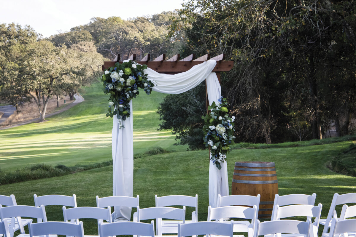 golf course at Napa Valley Country Club setup for a wedding ceremony with white chairs, white drapery and flowers