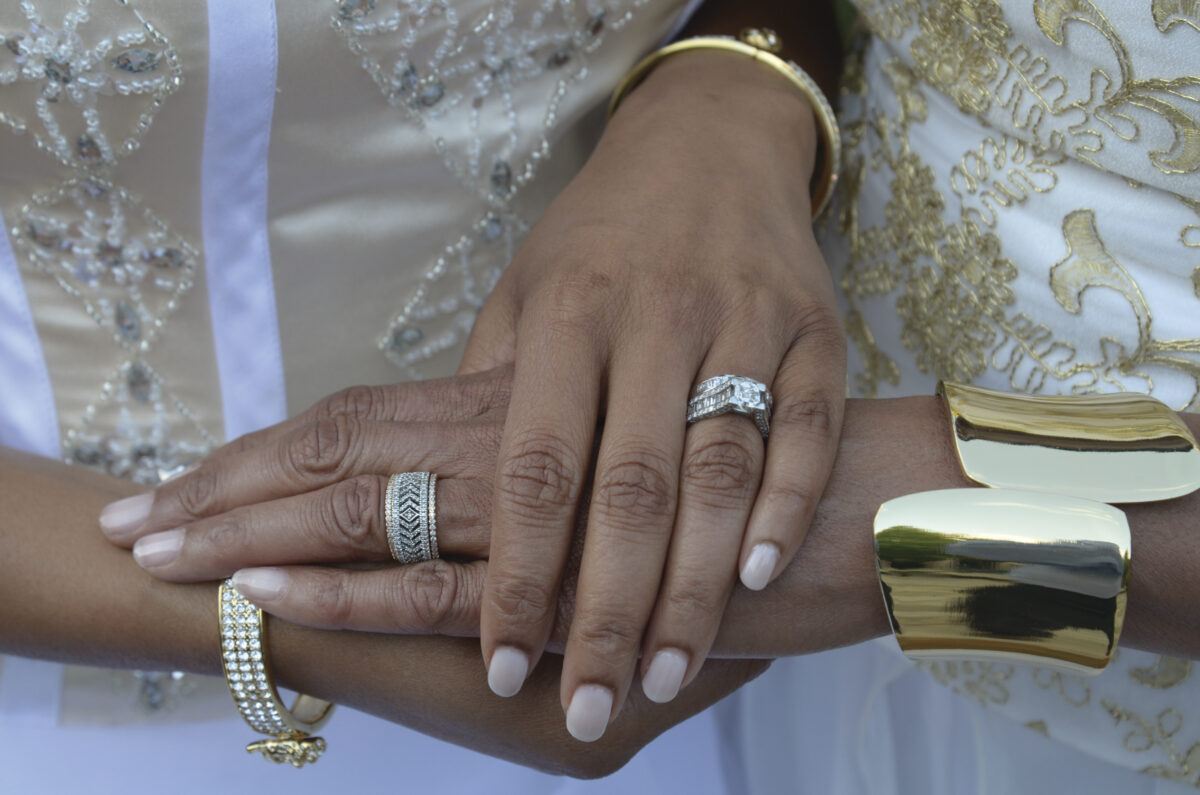 hands layered on top of each other with newly placed wedding rings