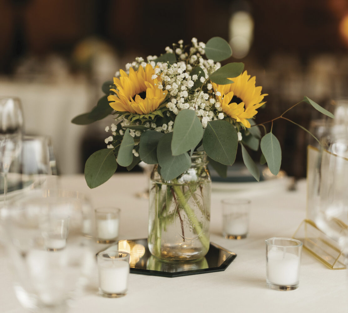 table setting with white tablecloth, candles and vase with sunflowers