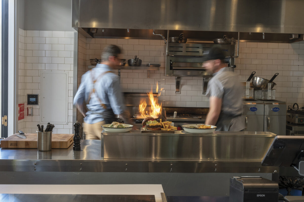 two chefs in kitchen at stove with fire