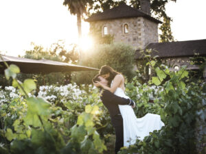 Groom lifting bride while kissing in the vineyard at V. Sattui
