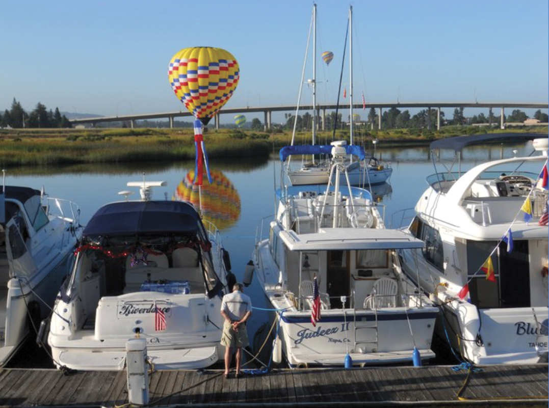 view of yachts docked with yellow hot air balloon in the background