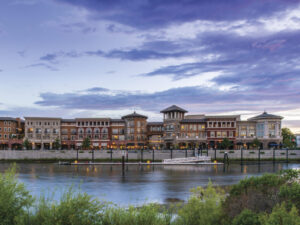 view of downtown Napa riverfront with green in forefront, blue sky and several building on waterfront