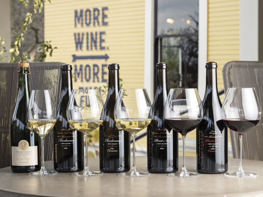 Five bottles of Frank Family Vineyards wine with wine glasses lined up for tasting, outdoors