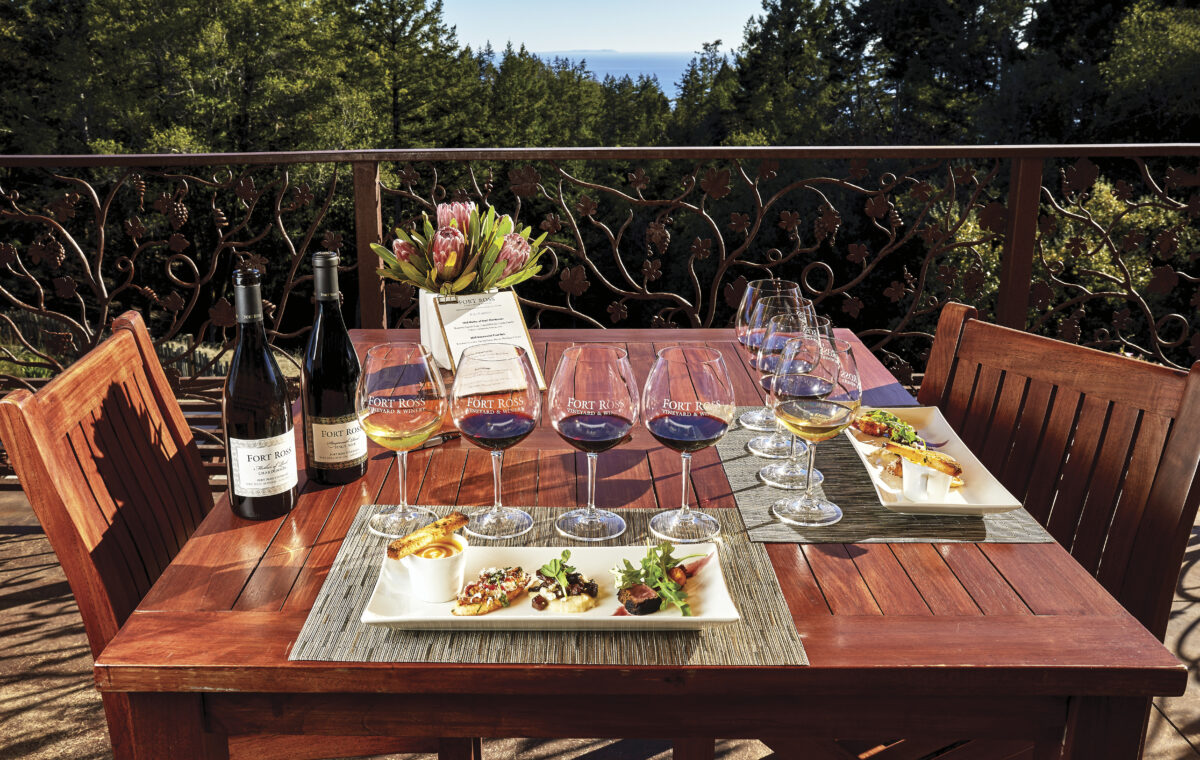 outdoor table at Fort Ross Winery with glasses and wine set up for a tasting with plates of food on white plates