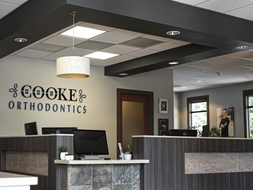 interior of Cooke Orthodontics office with logo on wall, with tests and reception are in brown and white