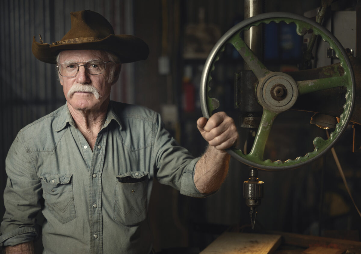 Randy Dunn in green shirt wearing a brown hat with hand on a wheel