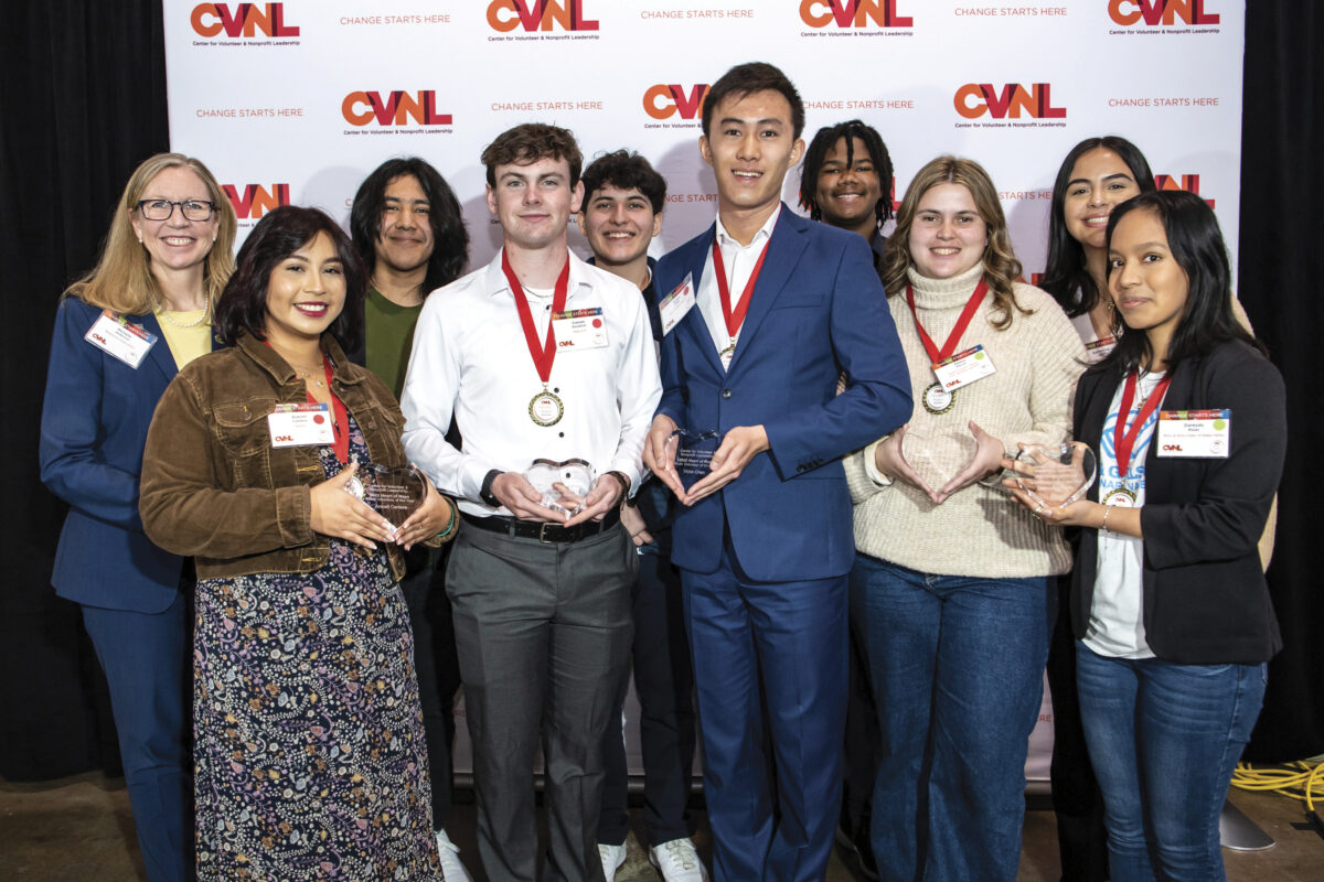 group of people with red bedals around necks holding an award