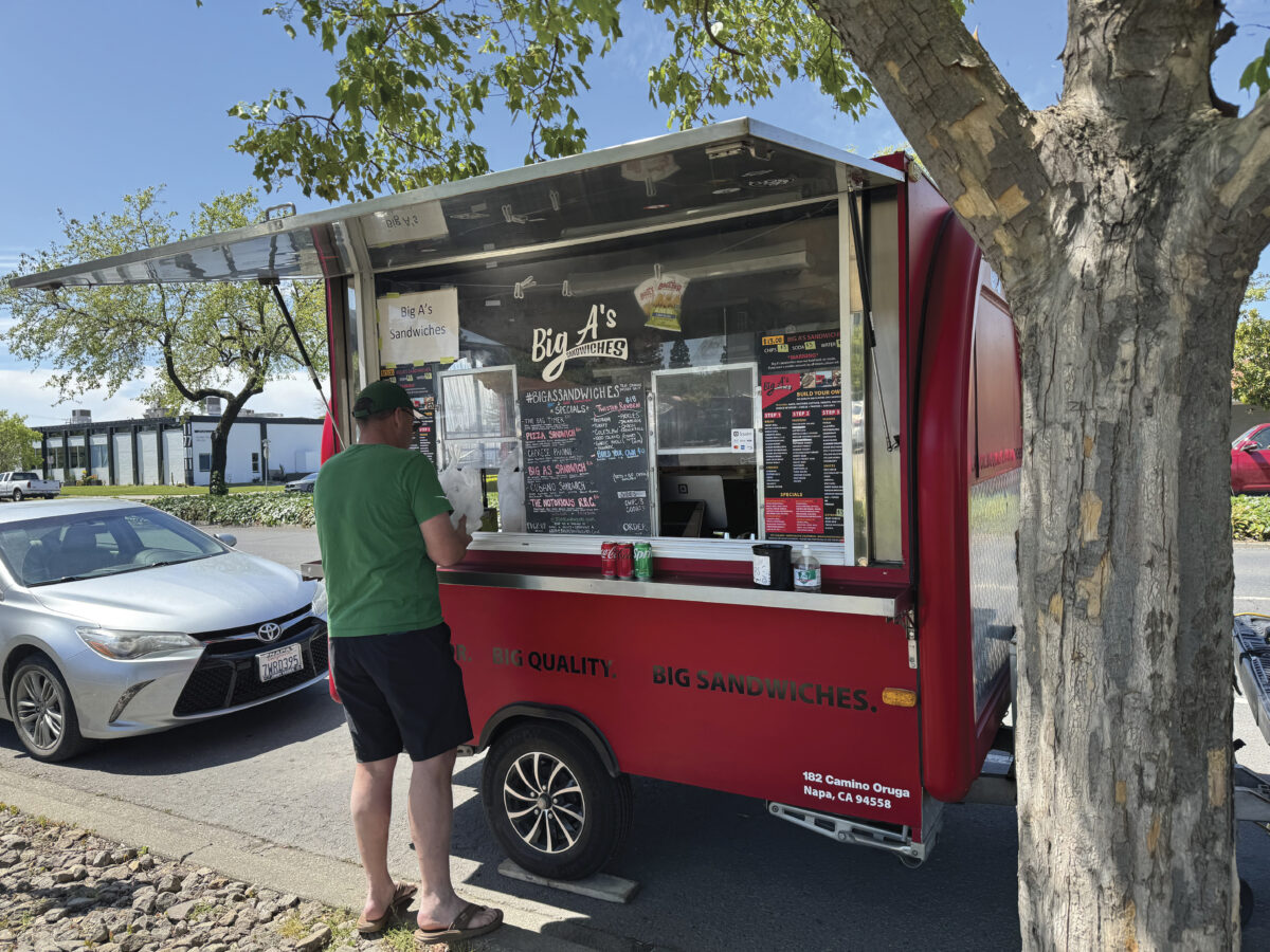 man standing at window ordering at red food truck