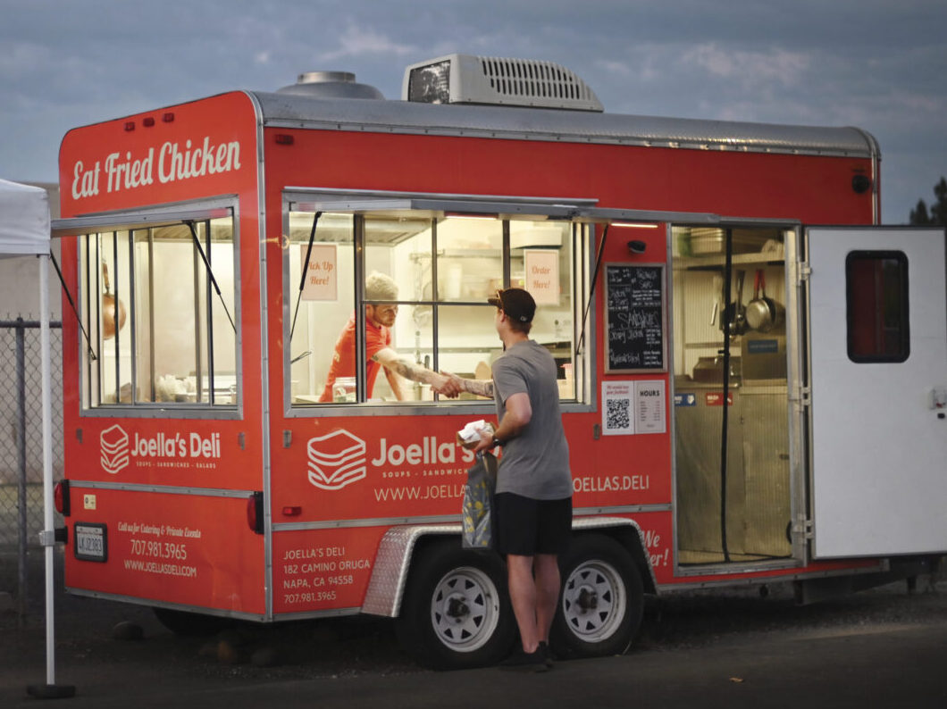 man ordering food from a red food truck at dusk