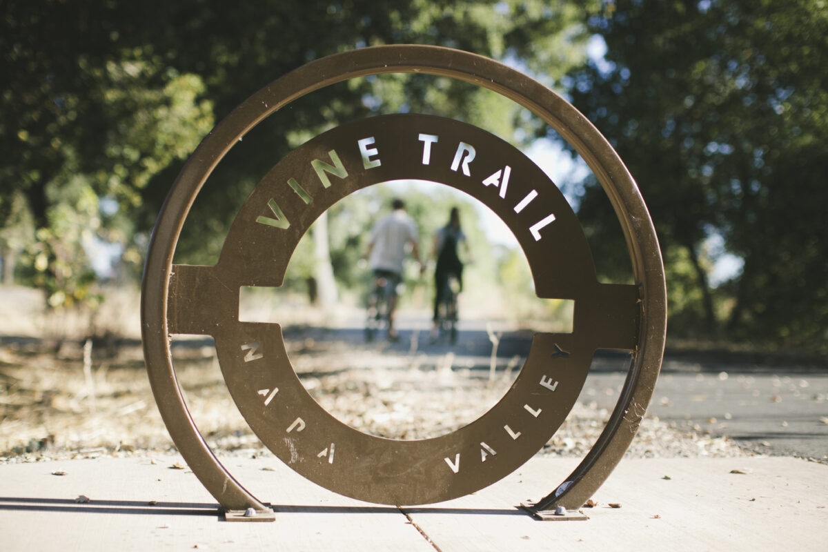 Napa Valley Vine Trail sign with road and trees in background