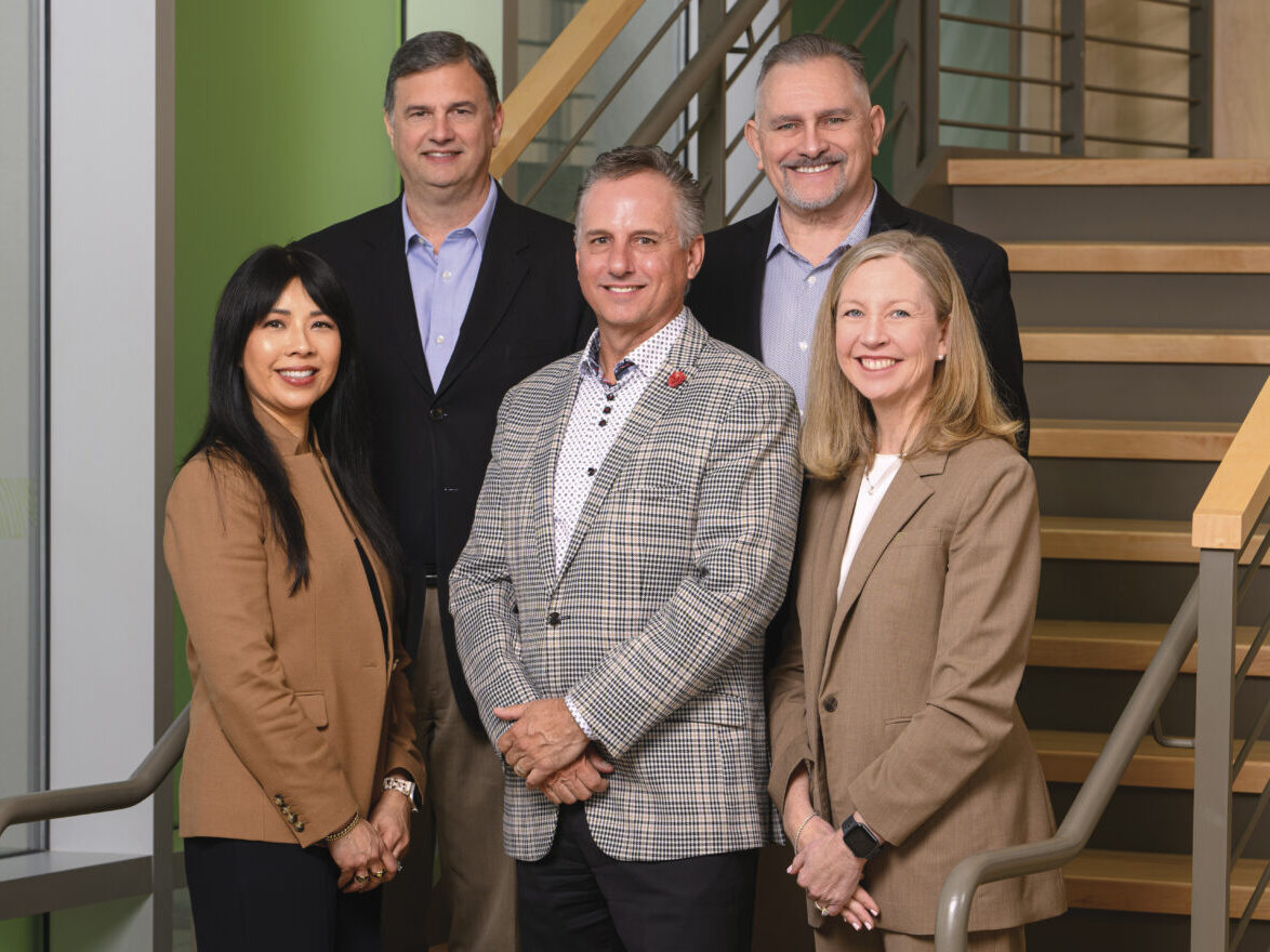 Five adults with Redwood Credit Union standing in front of a stairwell including Ron Felder, EVP/ CFO; Tony Hildesheim, EVP/ Chief Admin. Officer; Mishel Kaufman. EVP/COO; Brett Martinez, Pres/CEO; Michelle Anderson, EVP/Chief Lending Officer
