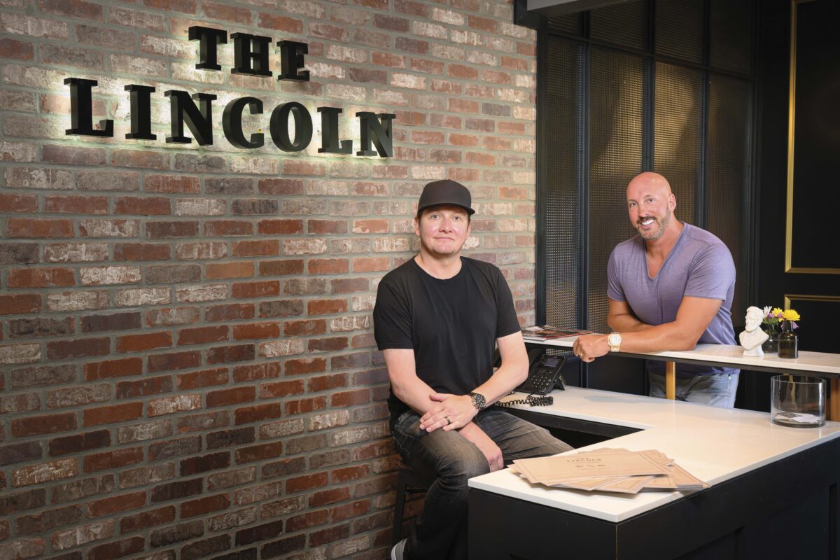 Adam Synder, Restaurateur, The Lincoln and Mike LeBlanc sitting at counter in front of brick wall with The Lincoln sign