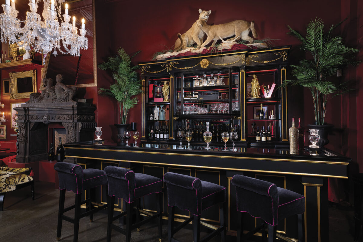 luxurious bar with black leather barstools with red walls, leopard on bar and chandelier