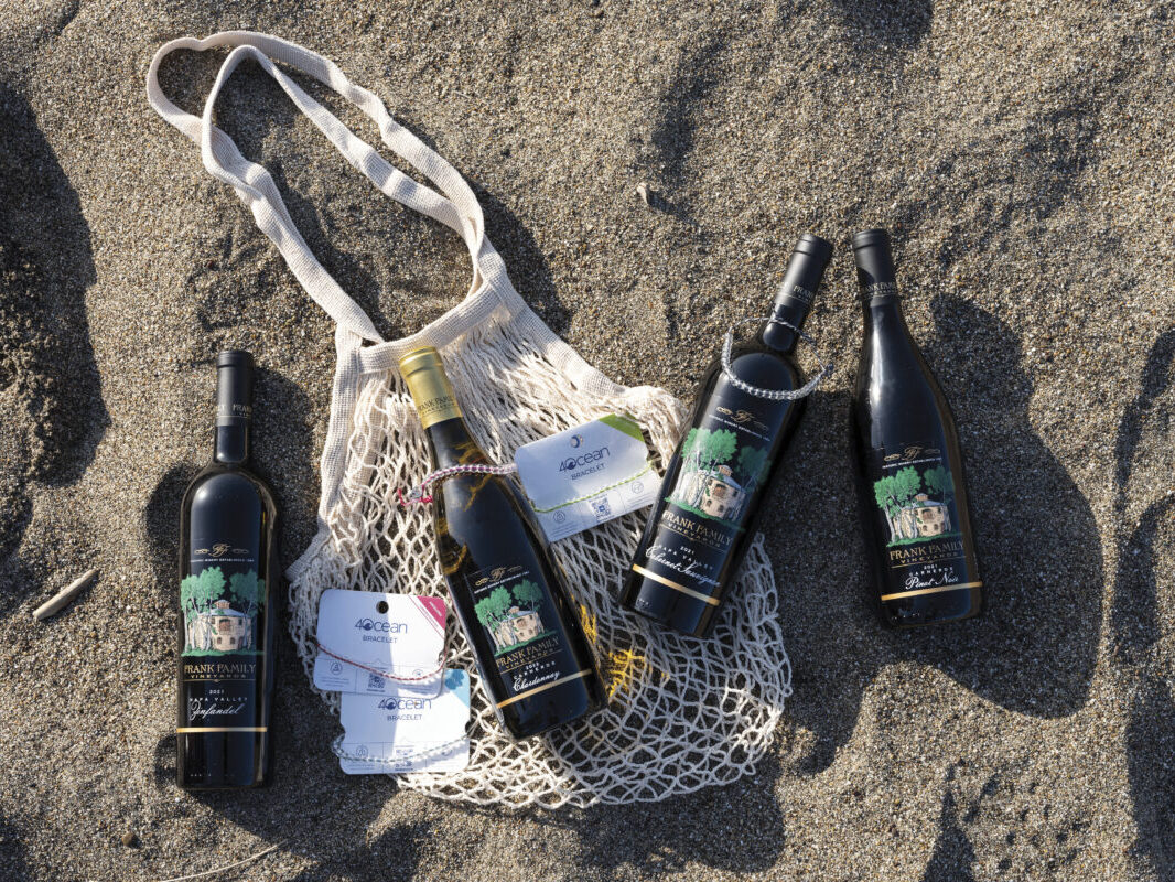 bottles of wine placed on sandy beach with bag and 4Ocean branded tags