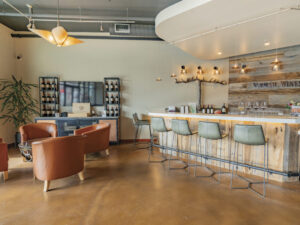 interior of Vermeil Wines tasting room with wood floors, bar with aqua barstools and seating area with leather chairs