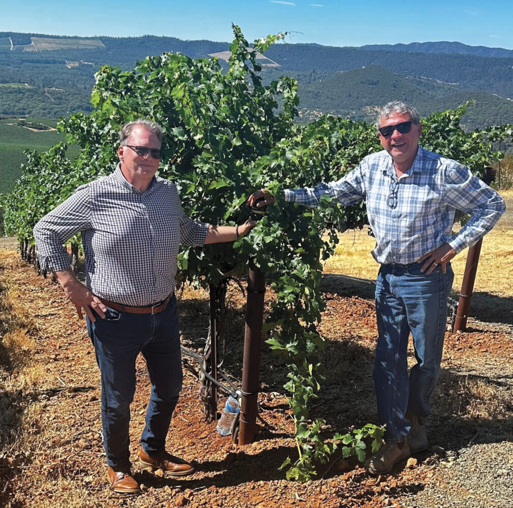 Brian Hilliard and Pedro Rubio of Beckstoffer in vineyard, smiling wearing sunglasses