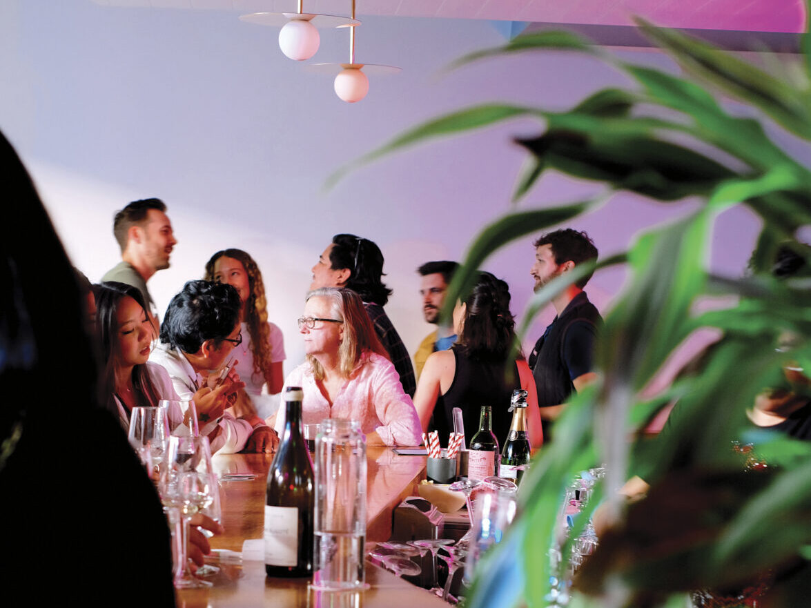 group of adults in bar setting with modern lights with pink and purple background for the article: Late Night Napa