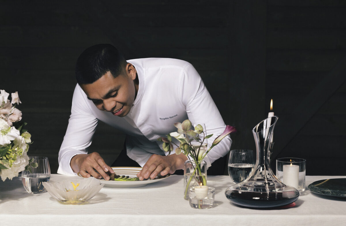 Chef Rogelio Garcia leaning over plate at Auro at Four Seasons Resort Napa Valley with black background