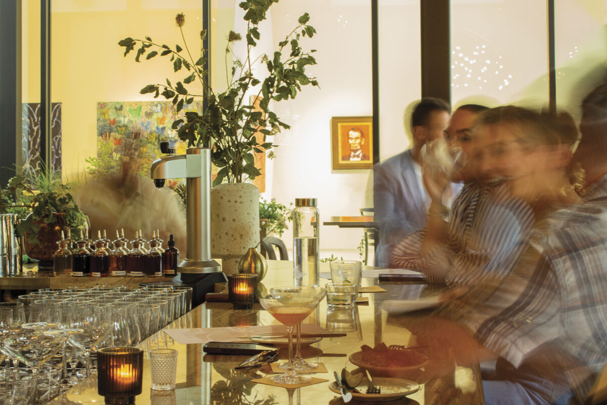 adults seated at bar with art and vase of greenery of the article Late Night Napa