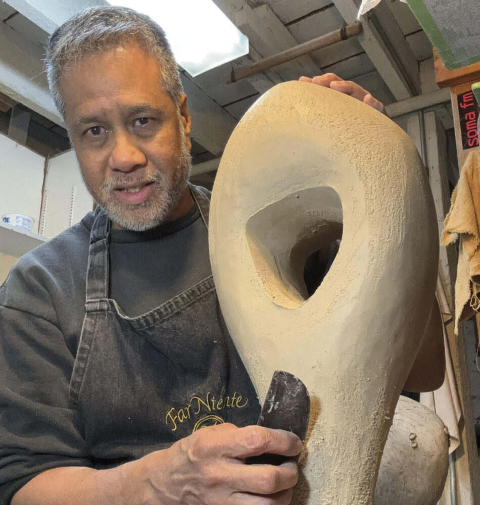 artist Emil Yanos standing with sculpture wearing apron