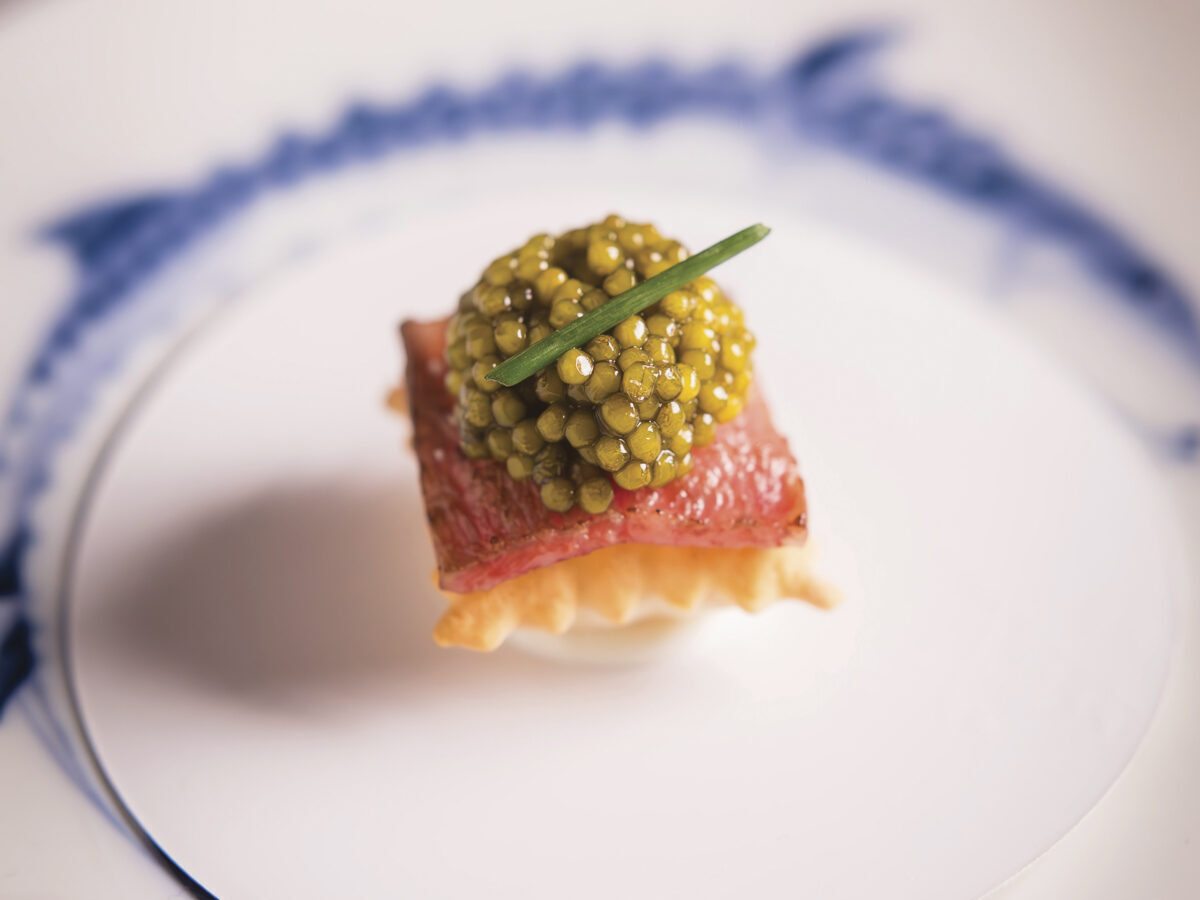 Golden Osetra Caviar Bite on white plate with blue trim at Auro