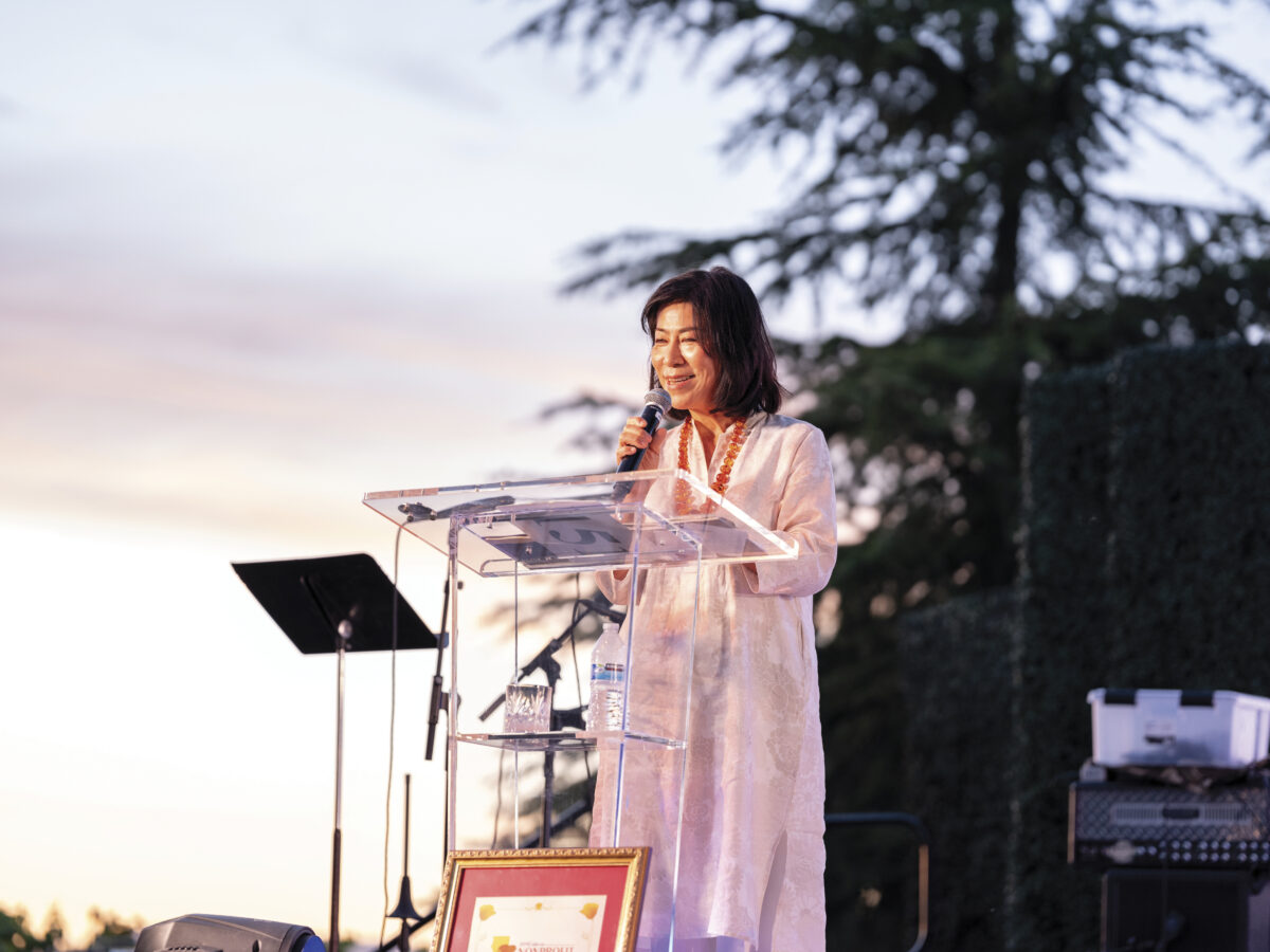 Naoko Dalla Valle speaks at Vida OLE Health Foundation outdoor at podium 